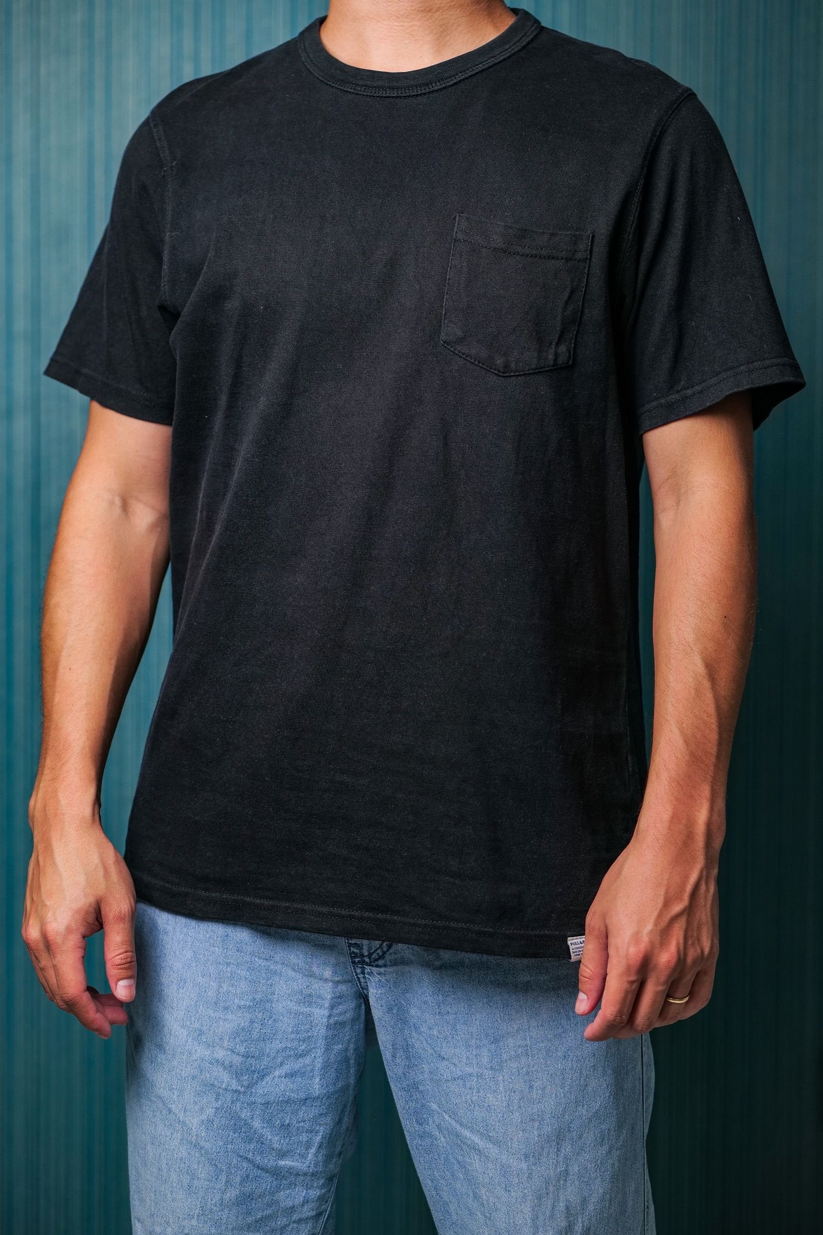 Homem com camiseta preta de manga curta e jeans azul