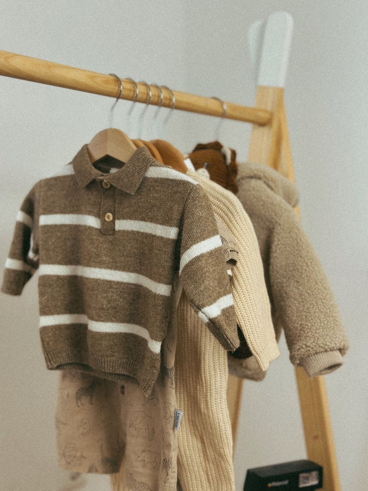 Roupas infantis de tricô em cabides, com peça marrom de listras claras na frente